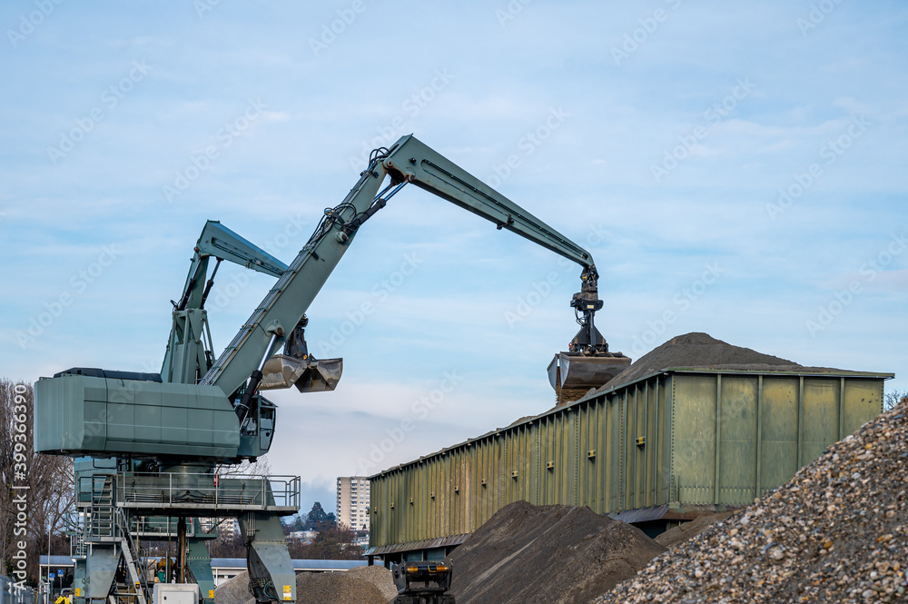 Big excavator working by handling pebbles from the pile of stones to container. Working machine in construction site.