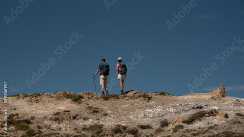 a young woman and a young man standing, side by side, looking at the horizon at the top of a mountain