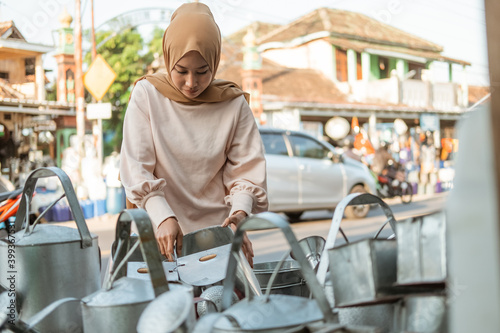 hijab woman stands when choosing watering can at the household appliances store