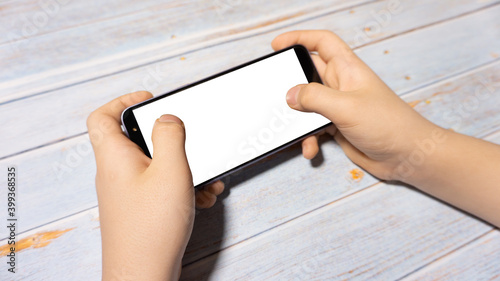 
The child is holding a phone with a white screen at the table. Child's phone with white screen