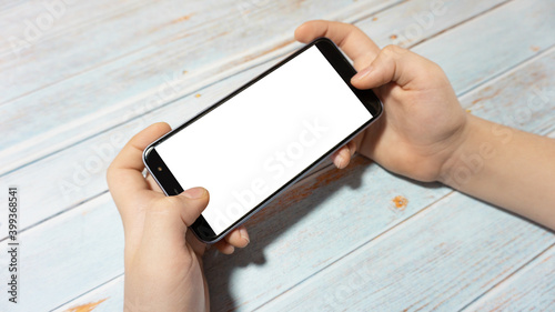 
The child is holding a phone with a white screen at the table. Child's phone with white screen