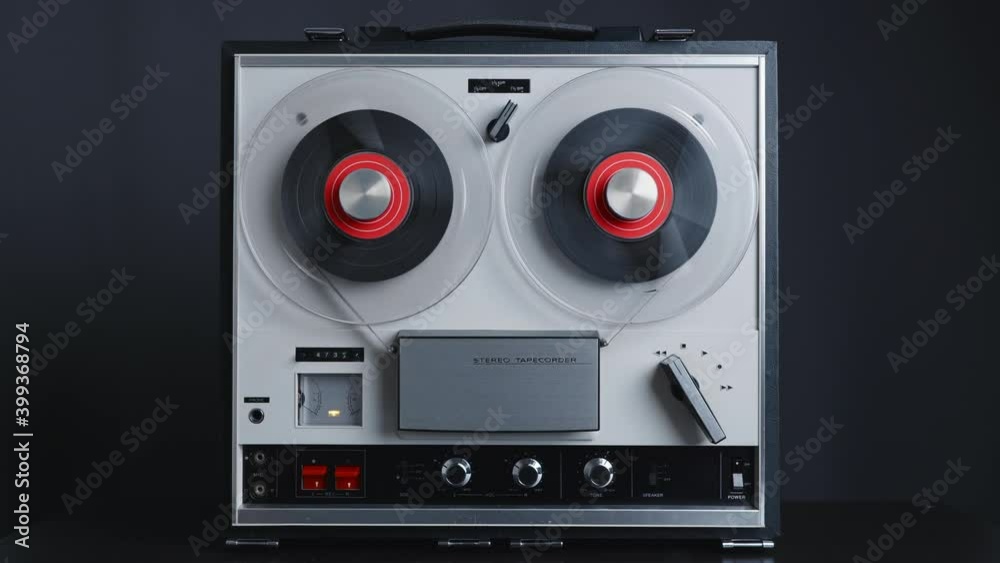 Man hand turns on music on reel to reel tape recorder playing. Rotating vintage music player close up. Retro tape. Spinning reel. Party. Loop. Front view. Front view. Popular Disco Trends 60s, 70s, 80 Man hand turns on music on reel to reel tape recorder playing. Rotating vintage music player close up. Retro tape. Spinning reel. Party. Loop. Front view. Front view. Popular Disco Trends 60s, 70s, 80