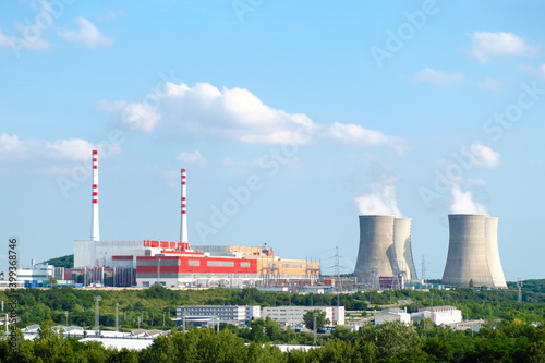 Panoramic view on nuclear power plant with steaming cooling towers on the background of blue sky