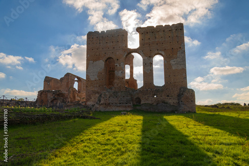 Photography Imposing remains of the Villa dei Quintili, Rome, the thermal baths, a suggestive panoramic of the caldarium and then frigidarium with the blue sky, clouds and shadows on the green lawn