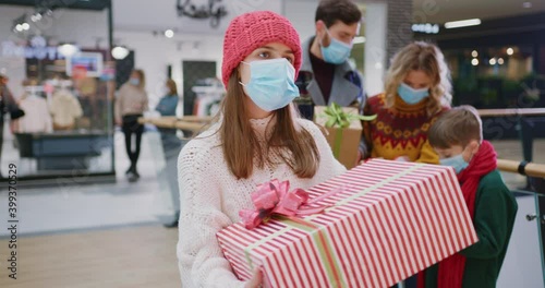 Portrait of excited pretty caucasian girll teenager dancign with her Christmas present enjoying holiday shopping with family smiling into camera. Family tradition. Christmas. photo