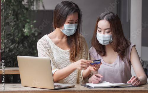 Women wearing masks and doing shopping online by using credit card for payment