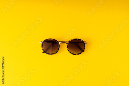Sunglasses in leopard pattern isolated top view on the yellow background.
