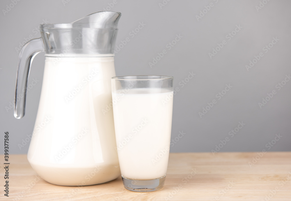  A jug and bottle of milk glass on a wooden table on background..Raw milk is high in calcium and protein to drink for all ages..Milk consumption nutritious and healthy dairy products concept..
