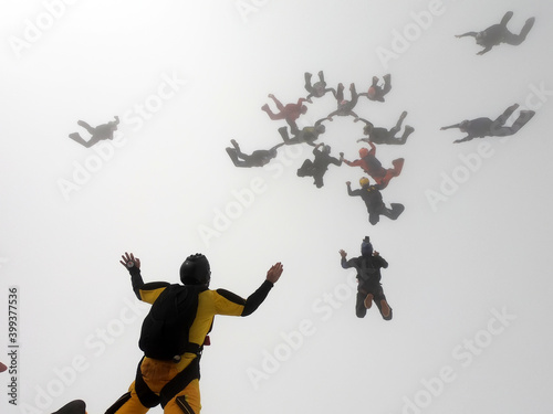 Skydiving formation inside the clouds.  The focus of the photo is on the yellow parachutist on the left.