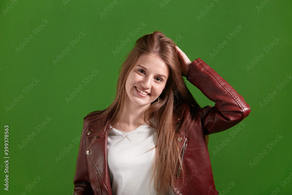 Happy beautiful smiling, laughing young woman looks at the camera. Green background. Long blond hair.