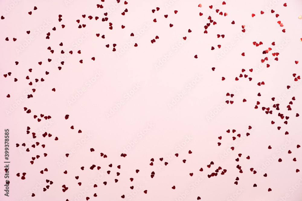 Frame border of red heart shaped confetti on pink background. Flat lay, top view, copy space. Happy Valentines Day, Mothers Day, birthday concept.