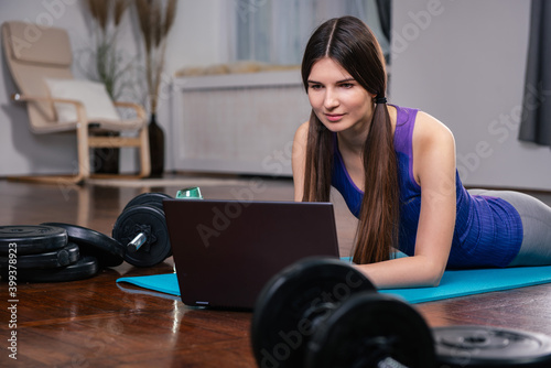 Young woman wearing sport outfit  watching online workout session on her laptop