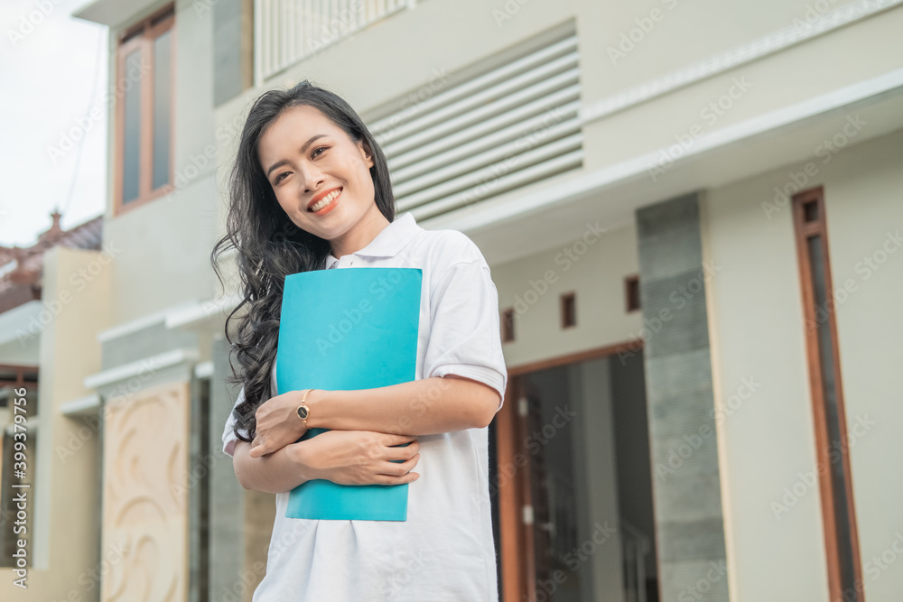 Asian beautiful woman standing holding home certificate in front of a new home Asian beautiful woman standing holding home certificate in front of a new home