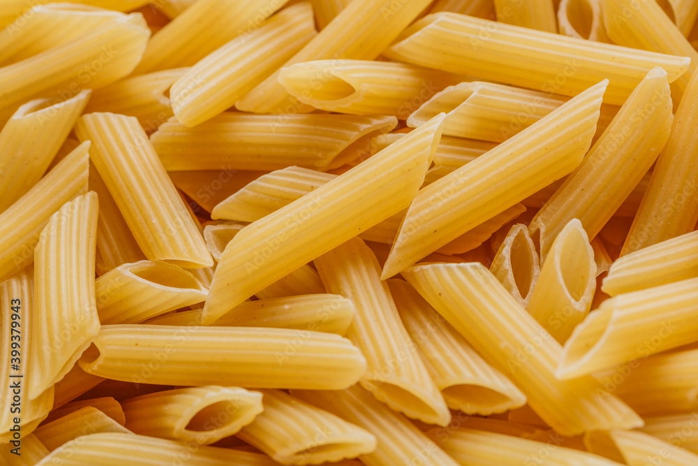 Dry pasta Pennoni Rigati.Pennoni Rigati have shape and yellow color. Pasta is delicious Italian traditional food made from wheat flour like noodles.Dry pasta background.Top view Dry pasta Pennoni Rigati.Pennoni Rigati have shape and yellow color. Pasta is delicious Italian traditional food made from wheat flour like noodles.Dry pasta background.Top view