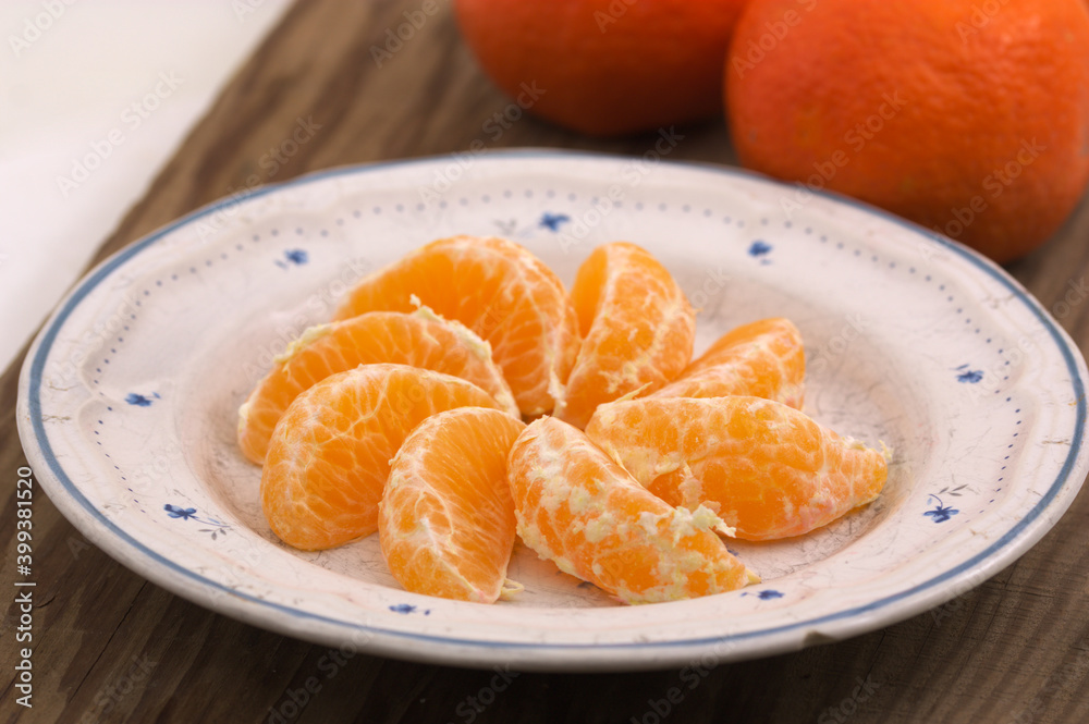 Plate with mandarin segments next to some whole mandarins