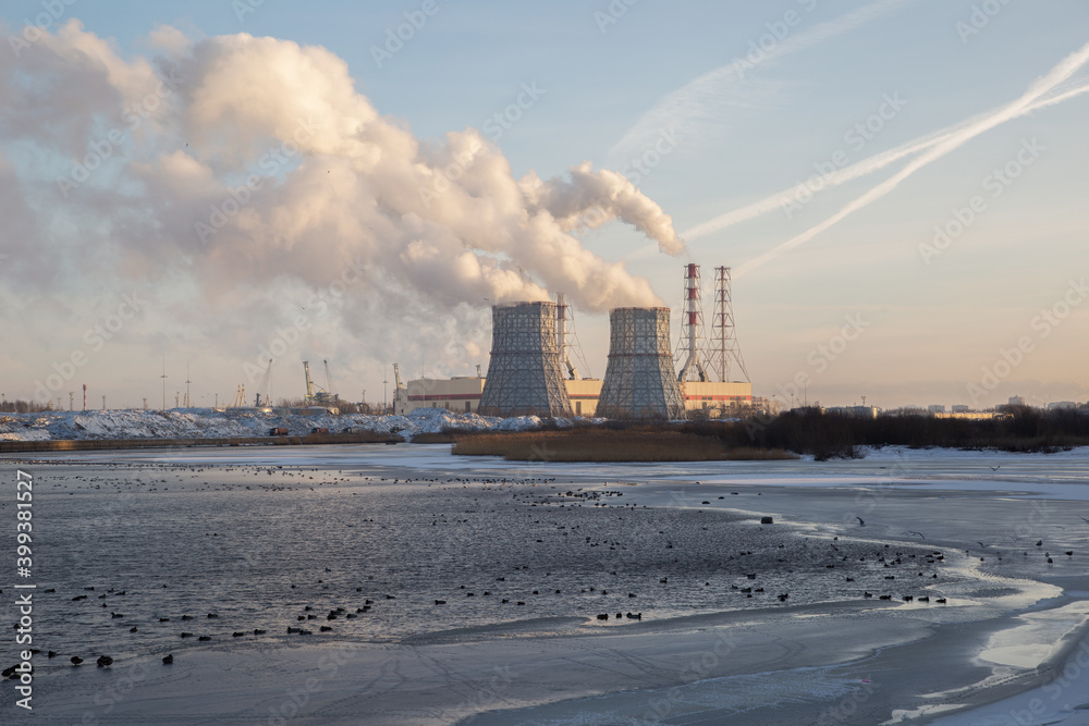 View of a power plant on the shores of the Gulf of Finland at dawn in winter. Southwest Thermal Power Plant Saint Petersburg Russia. Smoke from chimneys.