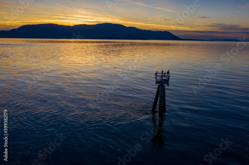 Sunset view from Lummi Island across Rosario Strait to Orcas Island in the San Juan Island archipelago. Chanel marker with cormorant birds in the foreground.