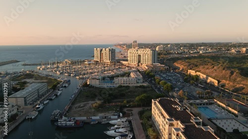 Aerial cinematic view of Herzlia marina full of sailboats, yachts and boats in Mediterranean city. View of hundreds sailboats during sunset in sea port during sunset, golden hour.