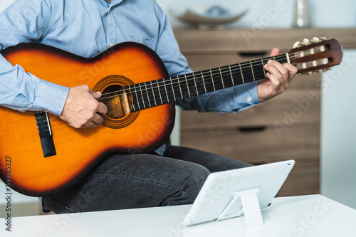 Caucasian male receiving online Spanish guitar lessons with the tablet