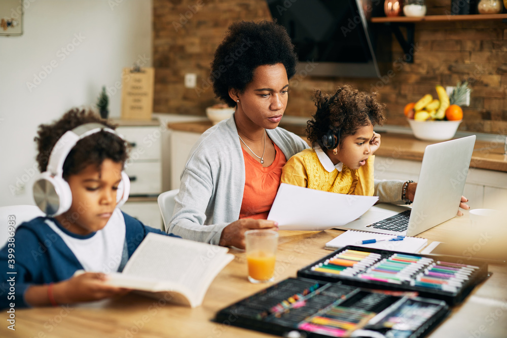 Fototapeta premium Working African American mother with son and daughter at home.