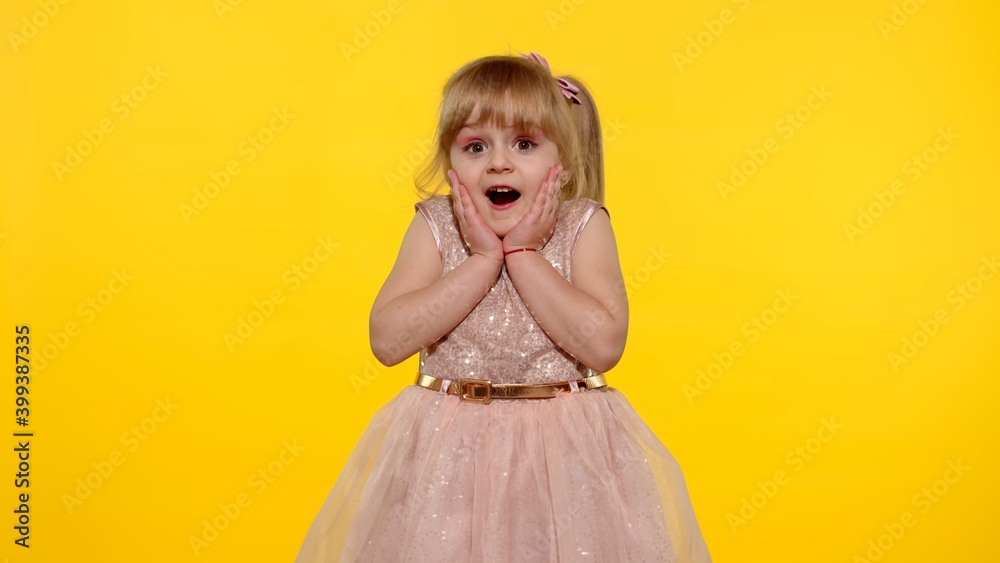 Portrait of happy amazed astonished young kid girl in shiny dress isolated on yellow copy space background. Impressed child. Perfect surprise. Exciting news. Wow reaction. Portrait of happy amazed astonished young kid girl in shiny dress isolated on yellow copy space background. Impressed child. Perfect surprise. Exciting news. Wow reaction.