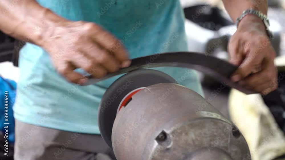 Sharpening the machete on sharpening machine. Worker sharpening machete with grindstone abrasive disc cutter machine.