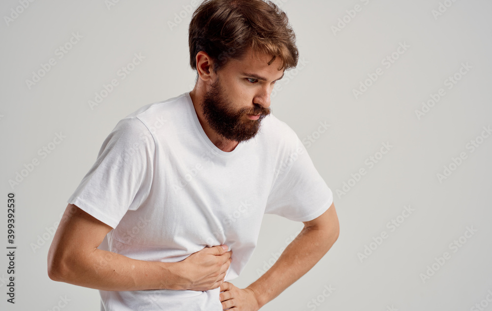 a man is in pain and touches his hand on a light background a man is in pain and touches his hand on a light background