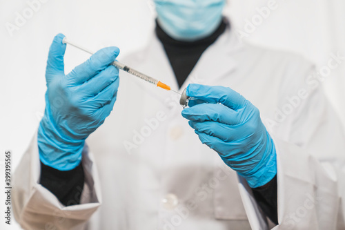 Doctor or scientist in the laboratory with a syringe with the cure of covid-19. Doctor preparing covid-19 or flu vaccine. Covid-19. Vial of vaccine. syringe. Flu vaccine. Coronavirus cure.