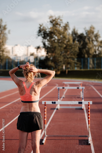 Female athlete preparing for hurdle race at stadium