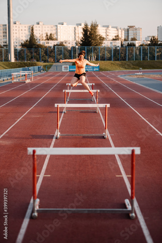 Powerful runner hurdling on marked sports road photo