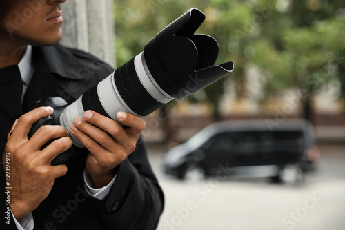 Obraz na płótnie Private detective with modern camera spying on city street, closeup