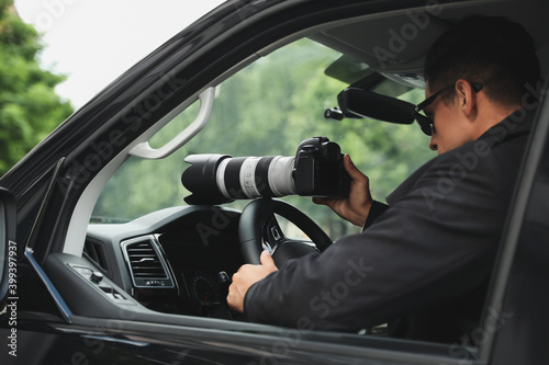 Private detective with camera spying from car