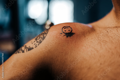 Crop man shoulder with smiling face tattoo on shoulder photo