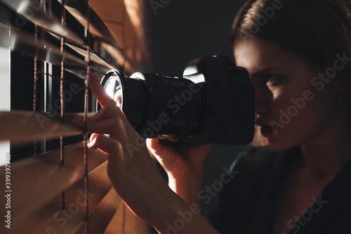 Fotografie Private detective with camera spying near window indoors