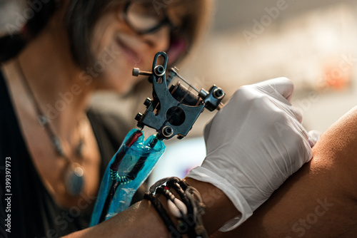 tattoo artist woman making tattoo for man photo
