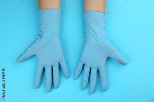 Person in medical gloves on light blue background, top view