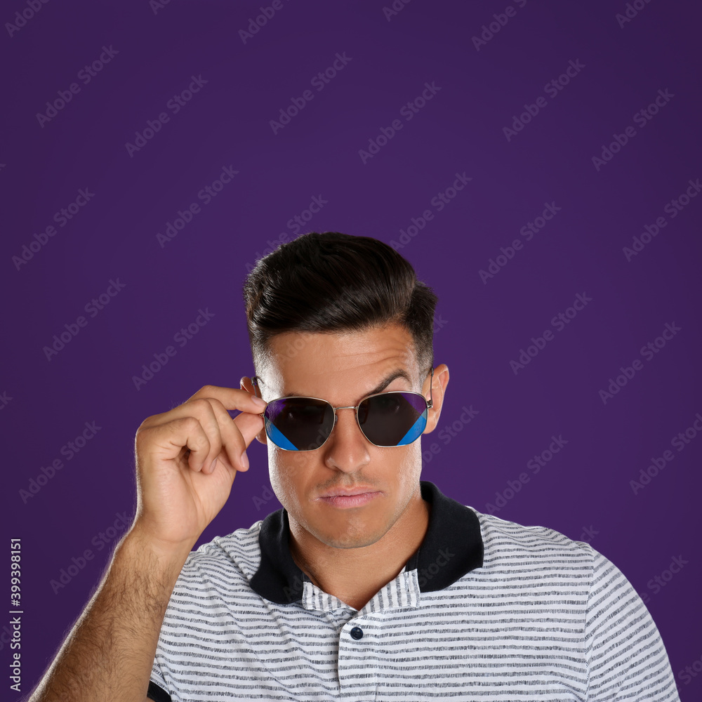Handsome man wearing sunglasses on purple background Handsome man wearing sunglasses on purple background