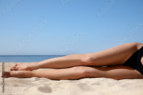 Young woman with beautiful body on sandy beach, closeup