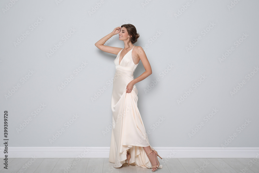 Young bride wearing beautiful wedding dress near light grey wall Young bride wearing beautiful wedding dress near light grey wall