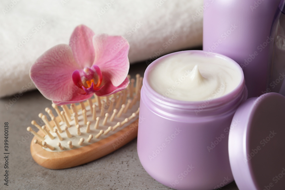 Different hair products, flower and brush on grey table, closeup Different hair products, flower and brush on grey table, closeup