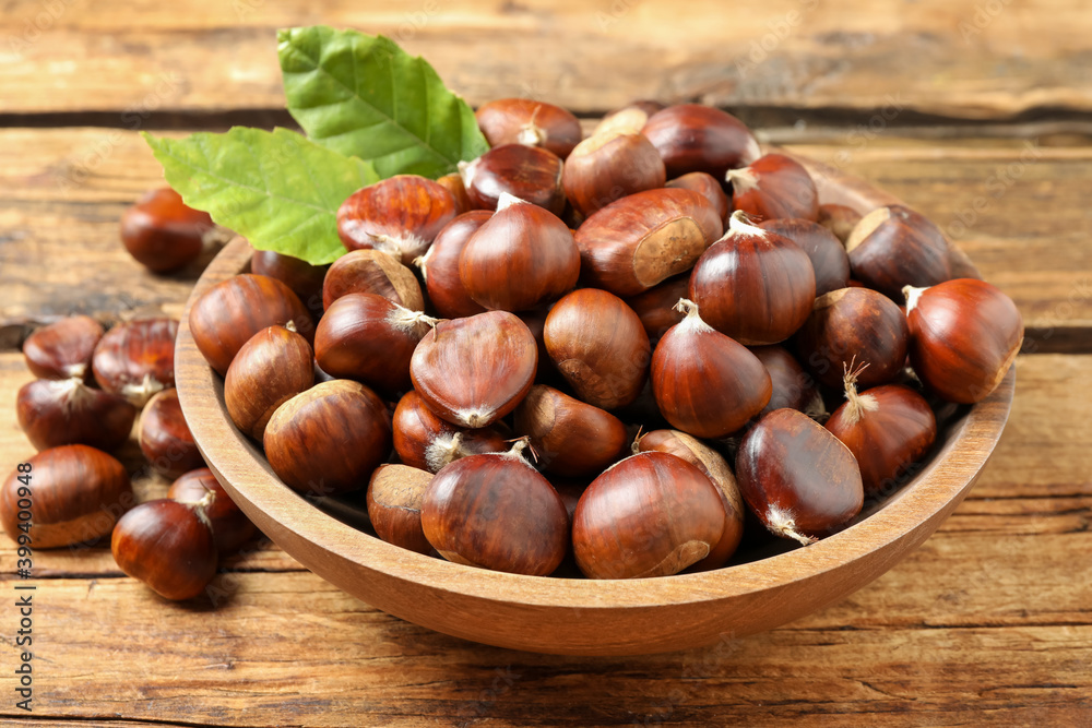 Fresh sweet edible chestnuts in bowl on wooden table Fresh sweet edible chestnuts in bowl on wooden table