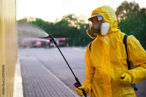 Person in hazmat suit disinfecting street with sprayer. Surface treatment during coronavirus pandemic © New Africa