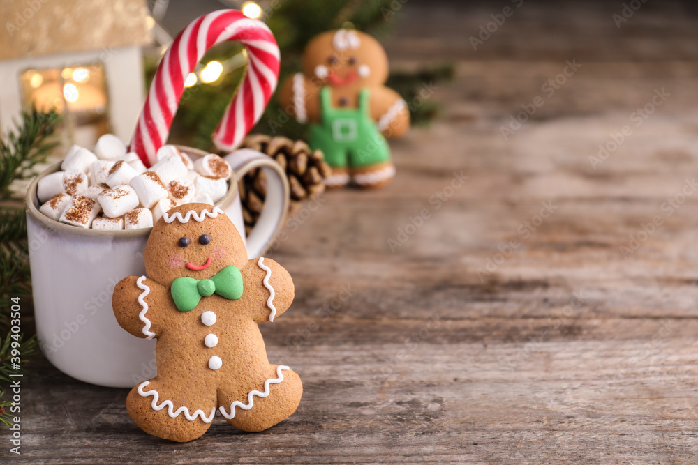 Gingerbread man and hot drink on wooden table, space for text