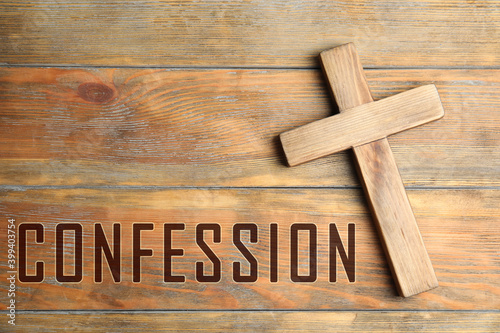 Christian cross and word Confession on wooden background, top view photo