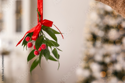 Foto Mistletoe bunch with red bow hanging indoors, space for text