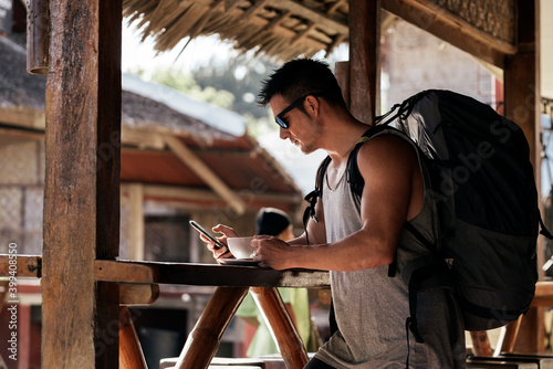 Man with a backpack using his phone and drinking coffee