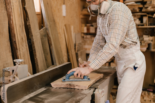 Carpenter using jointer planer in workshop