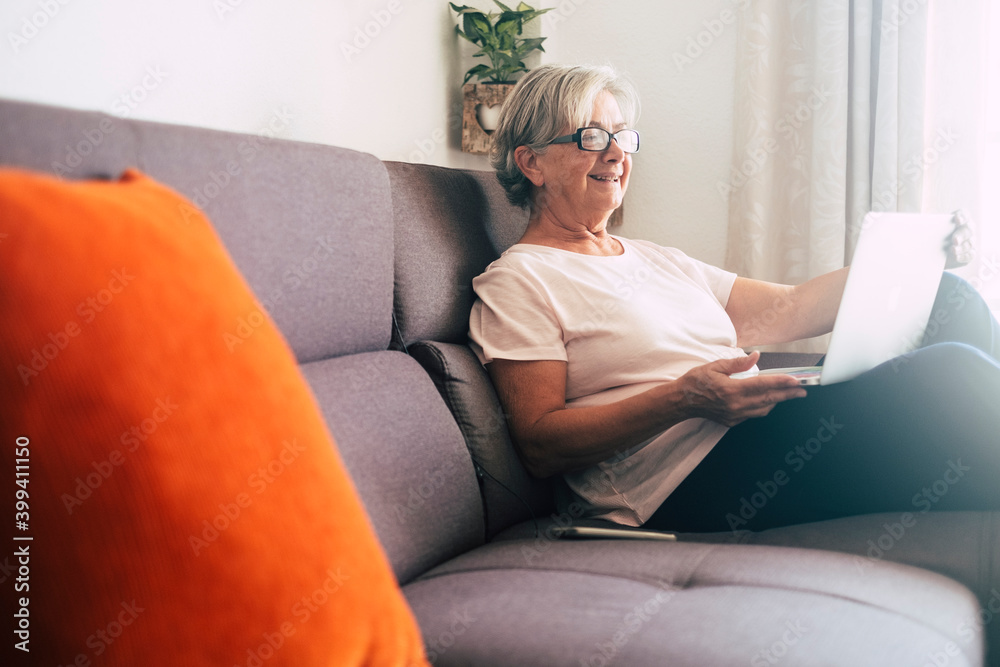 Smiling senior woman using laptop on sofa Smiling senior woman using laptop on sofa