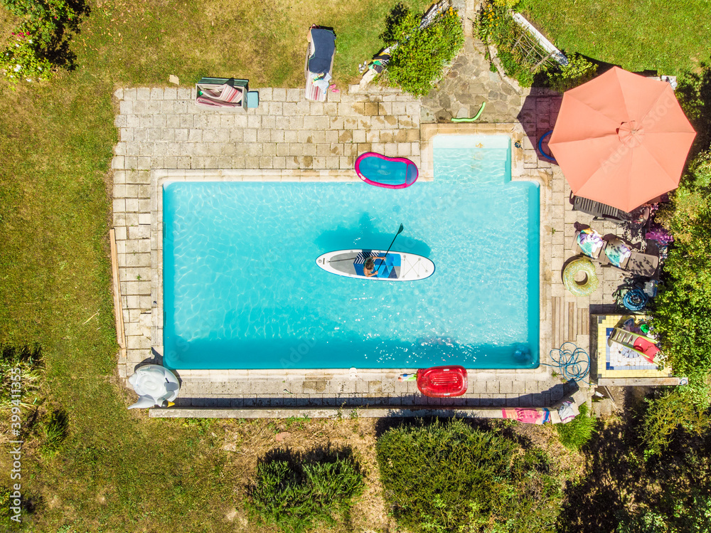 © AmazingAerialAgency - Aerial view of a woman on a SUP or stand up paddle in swimming pool.