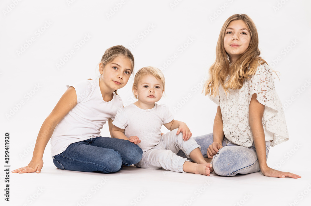 Blond sisters sitting against white background in studio Blond sisters sitting against white background in studio